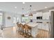 Bright open kitchen with white cabinets, island with seating, stainless appliances, and wood-look flooring at 304 Avery Glenn Way, Fuquay Varina, NC 27526