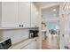 Kitchen area with white cabinets, stainless appliances, quartz countertop, tile backsplash and wood-look floors at 304 Avery Glenn Way, Fuquay Varina, NC 27526