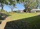 Large grassy backyard featuring mature shade trees, utility building, and carport at 305 Briarcliff Dr, Dunn, NC 28334