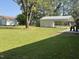 Spacious backyard with lush green grass, mature shade tree, and metal carport at 305 Briarcliff Dr, Dunn, NC 28334
