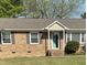 Charming brick home featuring a welcoming turquoise front door and well-maintained landscaping at 305 Briarcliff Dr, Dunn, NC 28334