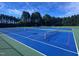 An outdoor tennis court with blue and green surfacing has net in place on a sunny day at 344 Colonial Ridge Dr, Pittsboro, NC 27312