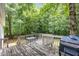 Wooden backyard deck featuring outdoor seating and a grill, surrounded by lush trees at 352 Riverstone Dr, Clayton, NC 27527