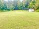 Expansive backyard with lush green grass, mature trees, and a charming storage shed at 4200 Harmony Church Rd, Efland, NC 27243