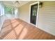 Covered porch featuring wooden floorboards and a white railing and a black painted door at 4200 Harmony Church Rd, Efland, NC 27243