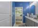 Bathroom with blue accent wall and gray cabinets viewed from bedroom at 5163 S River Rd, Lillington, NC 27546