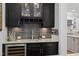 Stylish wet bar with dark cabinetry, granite countertop, tiled backsplash, and wine refrigerator at 623 Westfall Way, Chapel Hill, NC 27517