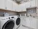 Bright laundry room with white cabinets, granite countertops, stainless steel sink, and washer and dryer at 67 Spring Hollow Ct, Pittsboro, NC 27312