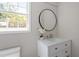 Bathroom features a modern vanity with marble countertop, round mirror, and natural light from the window at 7216 Carlton Dr, Raleigh, NC 27616