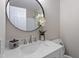 Bathroom features a modern vanity with marble countertop, round mirror, and decorative flower at 7216 Carlton Dr, Raleigh, NC 27616