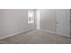 Bright bedroom with neutral walls, carpeted floors, a window, and a white door at 7216 Carlton Dr, Raleigh, NC 27616