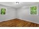 Bright bedroom featuring hardwood floors, fresh neutral paint, and two windows that bring in natural light at 833 Brigham Rd, Raleigh, NC 27610