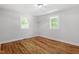 Inviting bedroom showcasing hardwood floors, two windows with verdant views, and freshly painted walls at 833 Brigham Rd, Raleigh, NC 27610