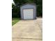View of blue metal shed with a garage door, showcasing extra storage and a paved driveway at 836 S Main St, Roxboro, NC 27573