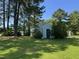View of a shed with a blue door, nestled amongst lush greenery and trees, providing ample outdoor storage at 8405 Falcon Crest Cir, Angier, NC 27501
