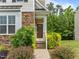 Inviting front entrance featuring a brown door, stone accents, and landscaped pathway with lush greenery at 100 Stratford Lakes Dr # 270, Durham, NC 27713