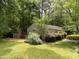 Backyard features a small deck and green lawn surrounded by mature trees and established plantings at 101 Solway Ct, Cary, NC 27511
