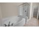 A tiled bathroom showcasing a shower with a glass enclosure and soaking tub with updated fixtures at 1020 Kingston Grove Dr, Cary, NC 27519