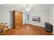 A bedroom with gray walls, hardwood floors, wooden wardrobe, ceiling fan, and wall mounted TV at 103 Lakeway Ct, Cary, NC 27511