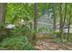 Back exterior displaying muted gray siding, brick foundation, and privacy fence amongst lush trees at 103 Lakeway Ct, Cary, NC 27511