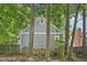Rear exterior showcasing muted gray siding and brick foundation, accented by mature trees for added privacy at 103 Lakeway Ct, Cary, NC 27511