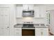 Modern kitchen featuring white cabinets, granite countertops, stainless steel appliances, and gold hardware at 103 Lakeway Ct, Cary, NC 27511
