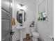 Elegant powder room with white fixtures, decorative mirror, stylish lighting and gray door at 105 Scotland Dr, Youngsville, NC 27596