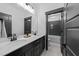 Bathroom featuring a dual sink vanity with black cabinets, quartz countertop, and a view into the tub-shower combo at 105 Scotland Dr, Youngsville, NC 27596