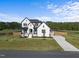 Stunning two-story home featuring a black roof, white brick, manicured lawn and a concrete driveway at 105 Scotland Dr, Youngsville, NC 27596