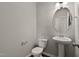 Neat half-bathroom with a pedestal sink, toilet, and a round mirror on the wall at 107 Explorer Dr, Morrisville, NC 27560