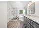 Bright bathroom featuring a soaking tub, glass enclosed shower and gray cabinets with granite countertop at 112 Sterling Ridge Way, Cary, NC 27519