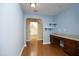 Blue bedroom with hardwood floors, a built-in desk with drawers, and access to other rooms at 120 Jennel Way, Durham, NC 27707