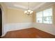 Formal dining room with elegant chandelier, wainscoting, hardwood floors, and a large window at 120 Jennel Way, Durham, NC 27707