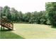 A sprawling, lush back yard with a soccer goal and a wooded backdrop and steps to a deck at 123 Scheer Ave, Durham, NC 27703