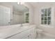 Bright bathroom with large mirror, white cabinets, and a window bringing in natural light at 124 Cypress View Way, Apex, NC 27502