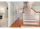 Hallway with hardwood floors, white trim, and staircase at 124 Cypress View Way, Apex, NC 27502