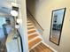 Staircase with wood treads, white risers, and a mirror reflecting the living space at 129 Friar Ln, Carrboro, NC 27510