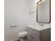 Bathroom features a sink with a wooden framed mirror, toilet, and towel bars at 1512 Bacon St, Durham, NC 27701