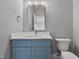 A modern bathroom features a vanity with blue cabinets, a toilet, and a mirror at 2521 Newbold St, Raleigh, NC 27603