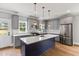 A modern kitchen features gray cabinets, a blue island, stainless steel appliances, and a white countertop at 2521 Newbold St, Raleigh, NC 27603
