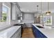 A modern kitchen features gray cabinets, a blue island, white countertops and stainless steel appliances at 2521 Newbold St, Raleigh, NC 27603