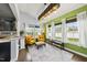 Sunlit sun room with yellow seating, a vibrant green accent wall, large windows, and stylish decor at 2909 Landon Pines Ct, New Hill, NC 27562