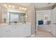 Bathroom featuring dual sink vanity with white cabinets, large mirror, and access to another room at 300 Quarryrock Road Rd, Holly Springs, NC 27540