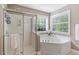 Bathroom showcasing a shower, soaking tub with jets, and a window bringing in natural light at 300 Quarryrock Road Rd, Holly Springs, NC 27540