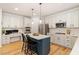 Modern kitchen with stainless steel appliances, white cabinets, a blue island, and hardwood floors at 300 Quarryrock Road Rd, Holly Springs, NC 27540