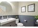 Stylish half-bathroom with geometric wallpaper, gray wainscoting, and a modern sink at 300 Quarryrock Road Rd, Holly Springs, NC 27540