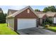Side angle of a brick home featuring a white two car garage, dark shutters, and manicured landscaping at 3027 Maple Ave # U1, Burlington, NC 27215