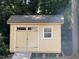 Backyard shed with a window and double doors that is surrounded by tall trees and foliage at 3205 Broyhill Cir, Raleigh, NC 27604