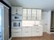 White kitchen includes built-in double ovens and glass-front cabinets with modern hardware and lighting at 3205 Broyhill Cir, Raleigh, NC 27604