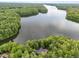 Aerial view of home secluded in a vibrant forest, featuring a tranquil lake view in the distance at 343 Lakewood Pointe Dr, Roxboro, NC 27574